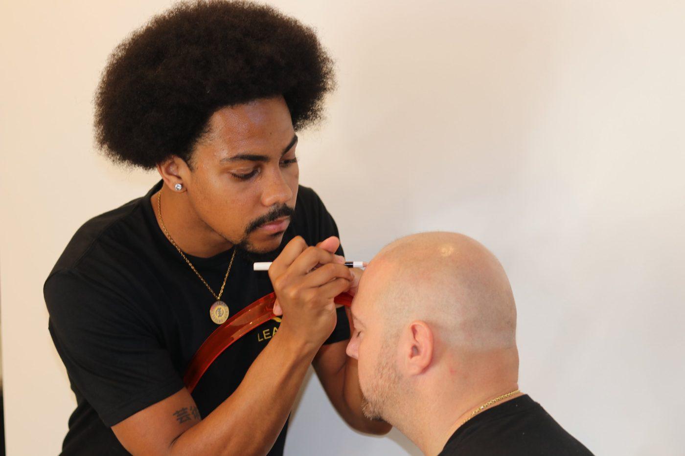 Alex drawing a client's hairline with a hairline guide before starting SMP